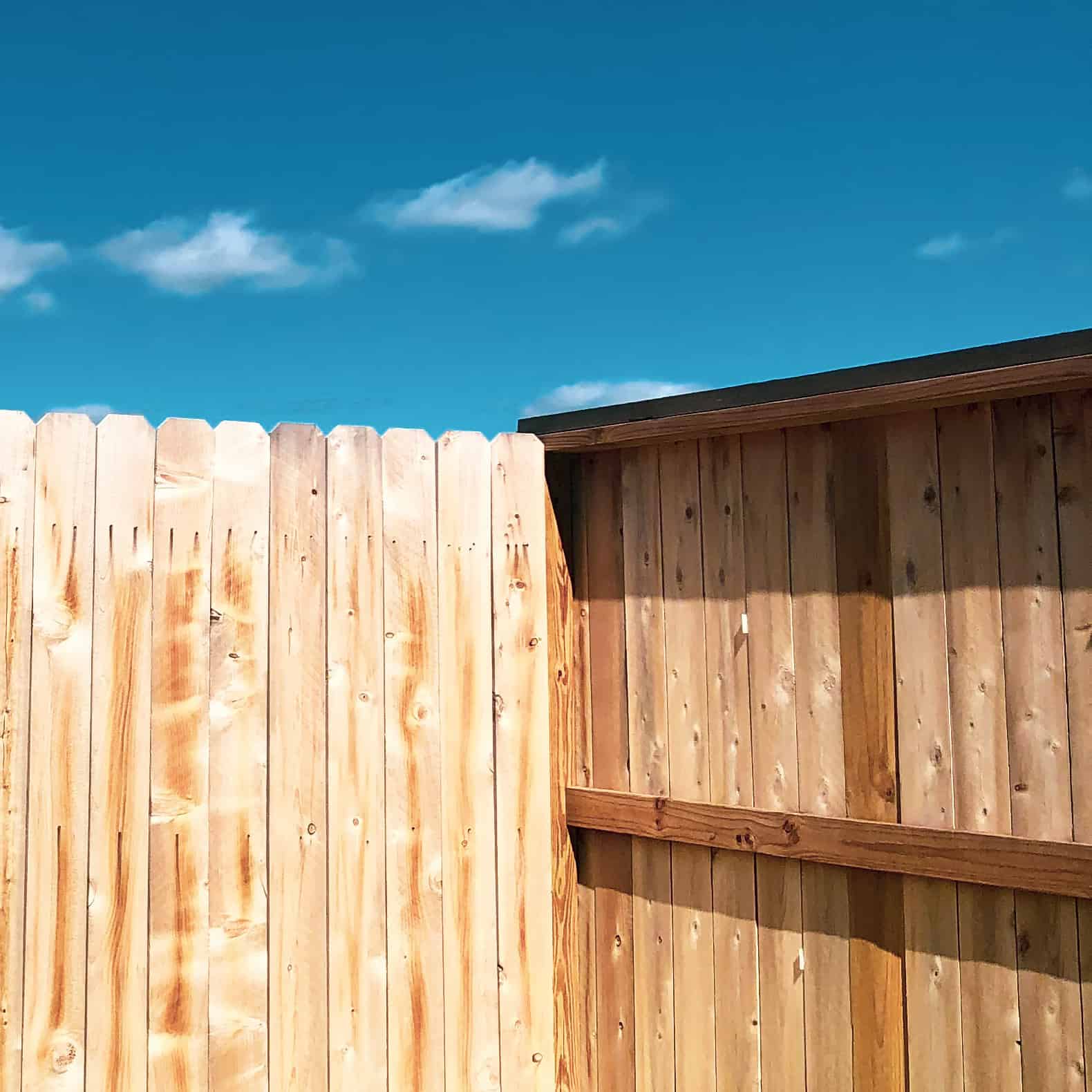 wooden fence with partly cloudy blue skies