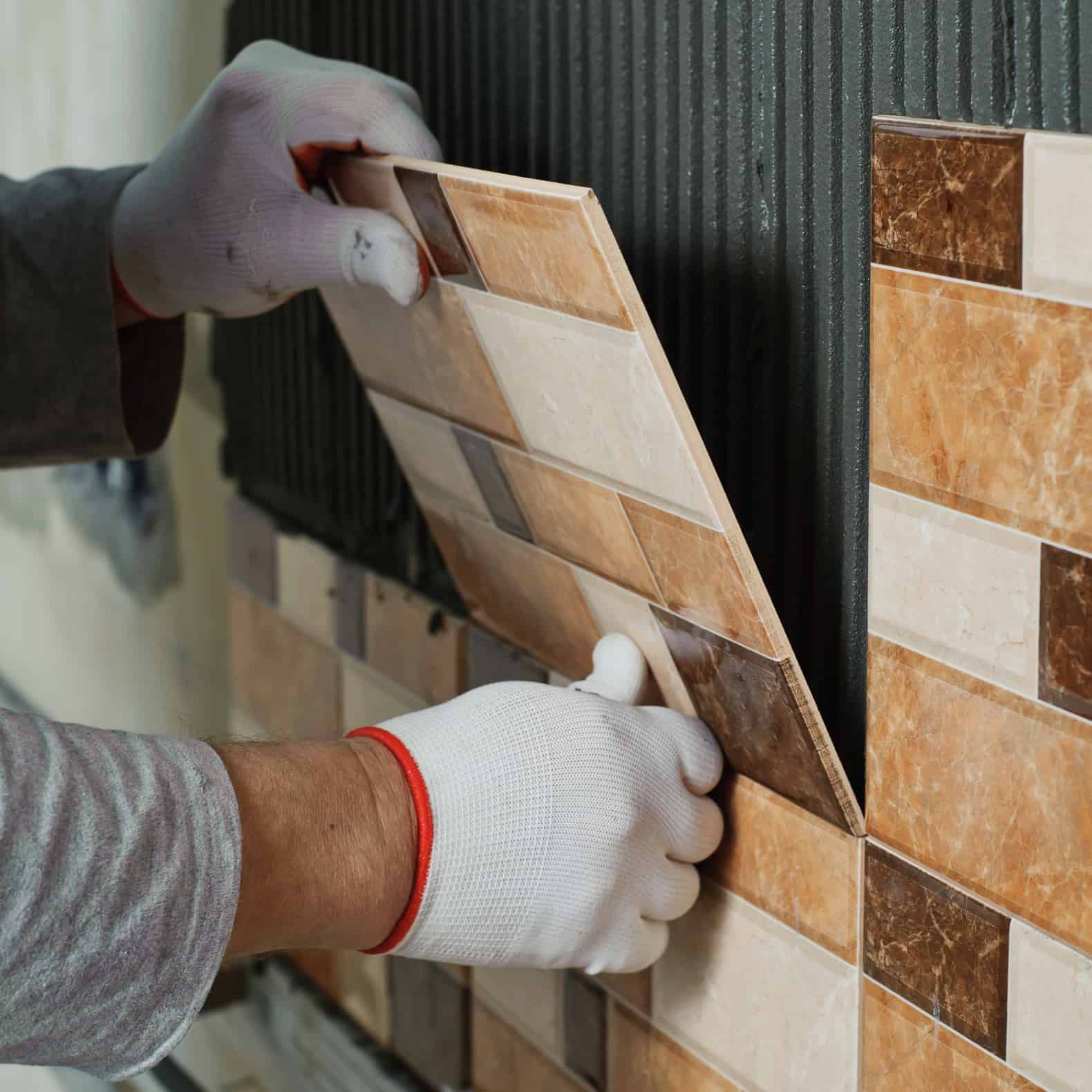 Worker setting multicolored tiles on the wall