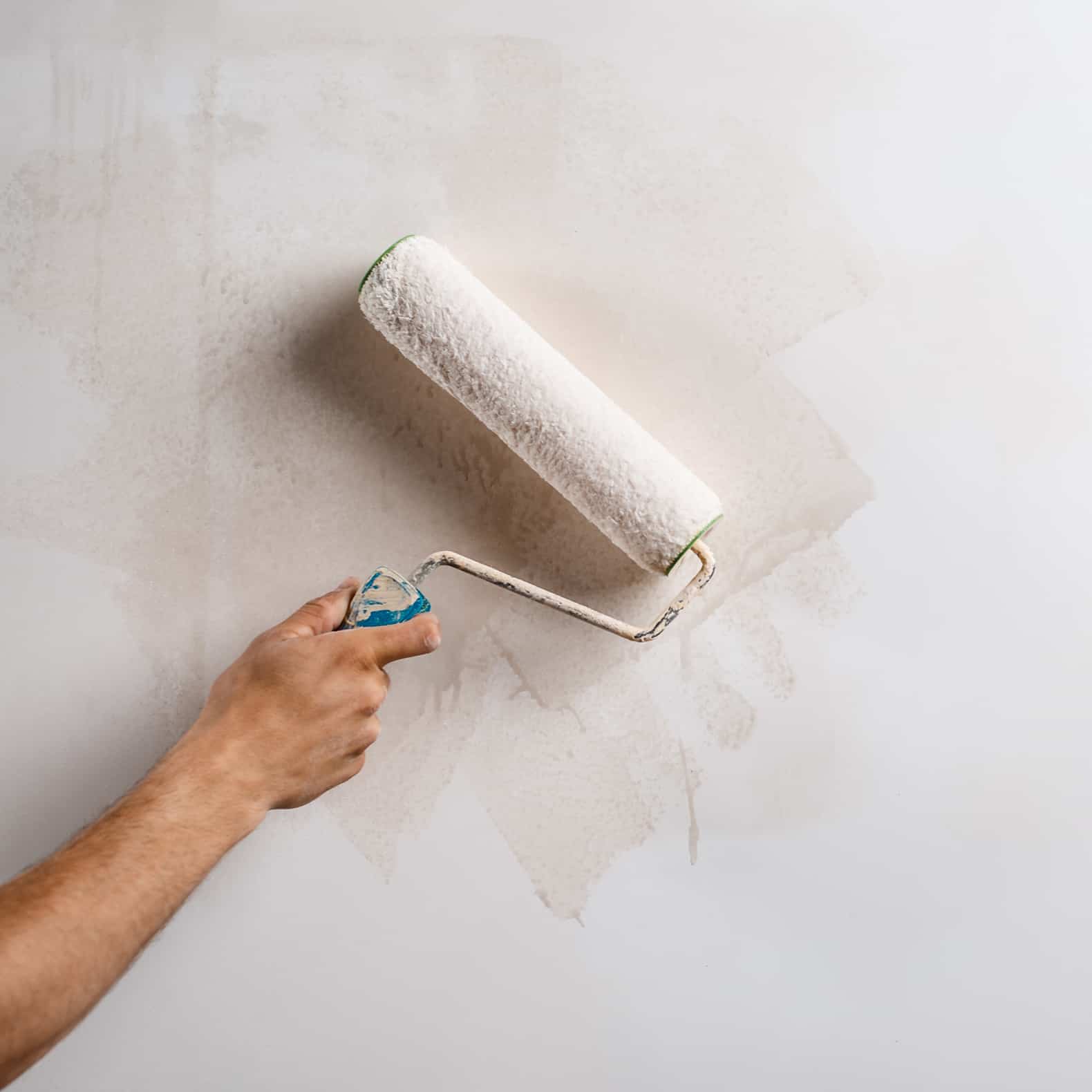 painter using a roller to paint the walls off white